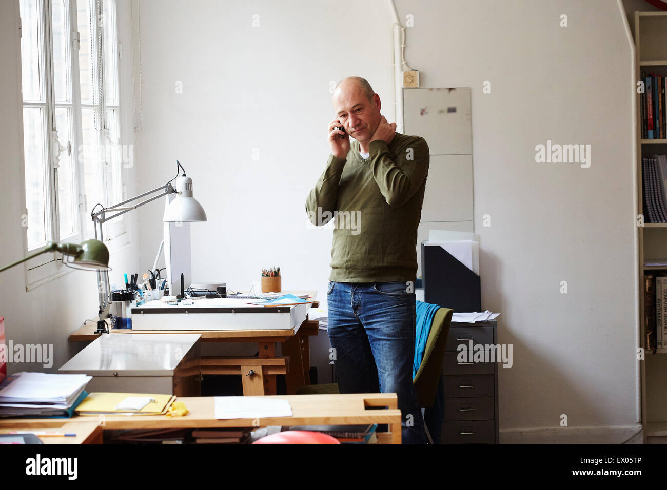 Reifer Mann am Telefon im Kreativstudio Stockfoto