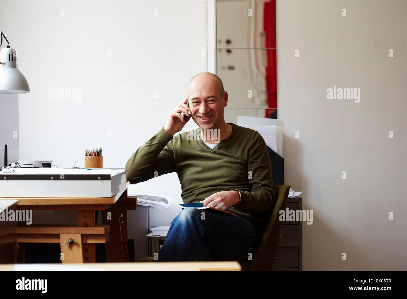 Reifer Mann am Telefon im Kreativstudio Stockfoto