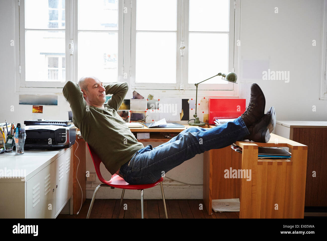 Reifer Mann mit Füßen sitzend am Schreibtisch Stockfoto