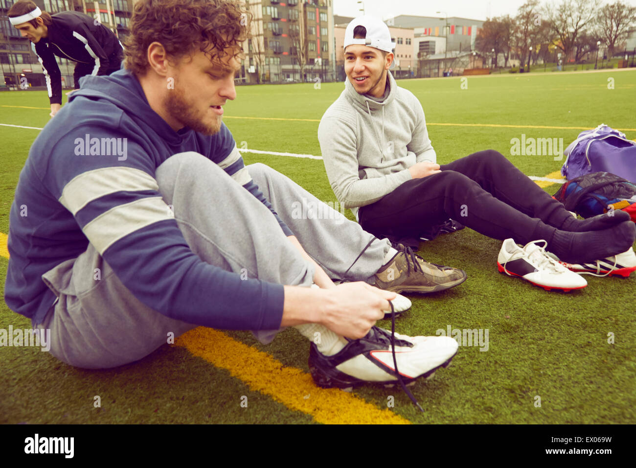 Männlichen Erwachsenen Freunden Boot Schnürsenkel binden, am Fußballplatz Stockfoto