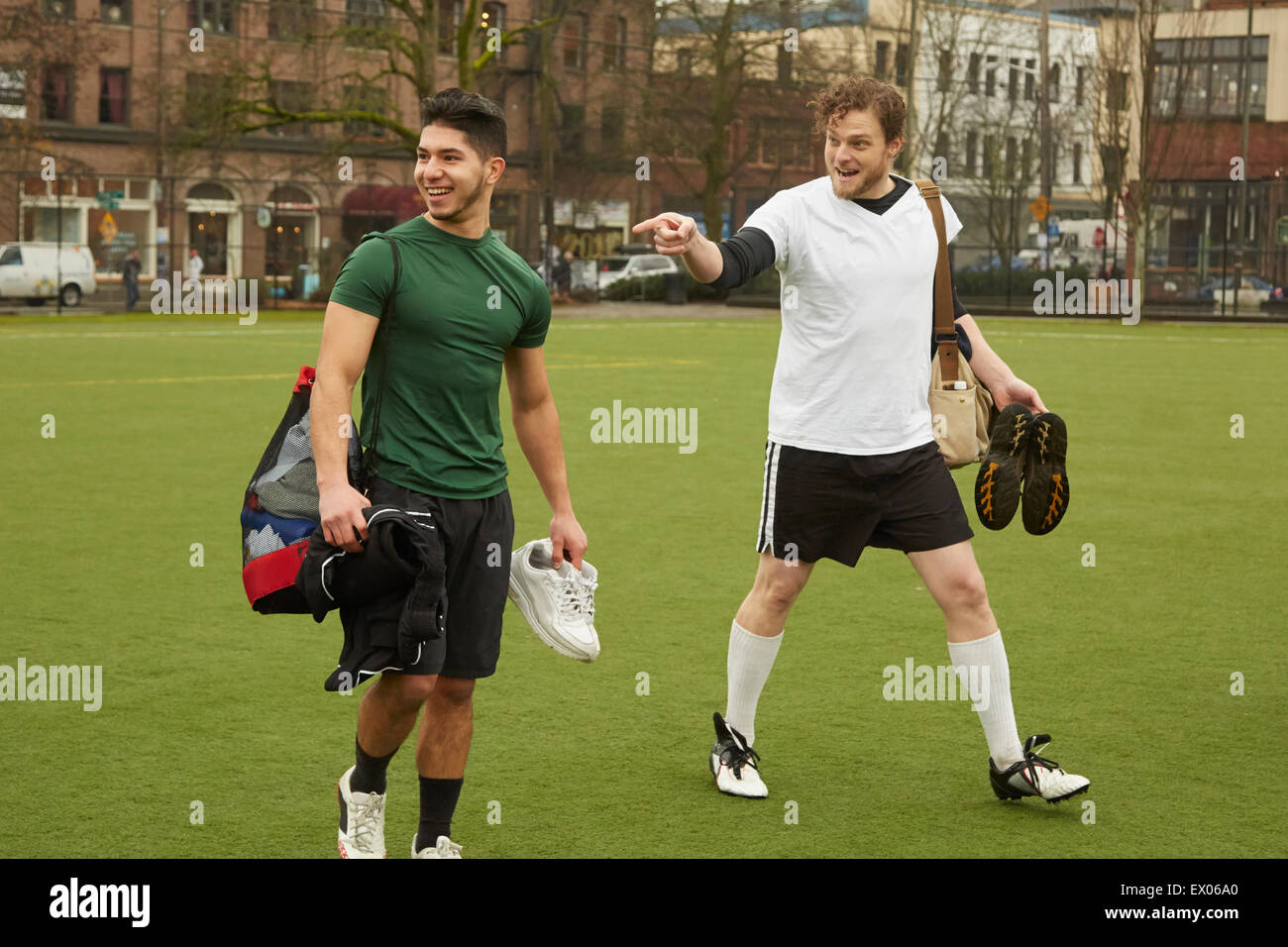 Zwei männliche Fußball-Spieler tragen Sporttaschen am Fußballplatz Stockfoto