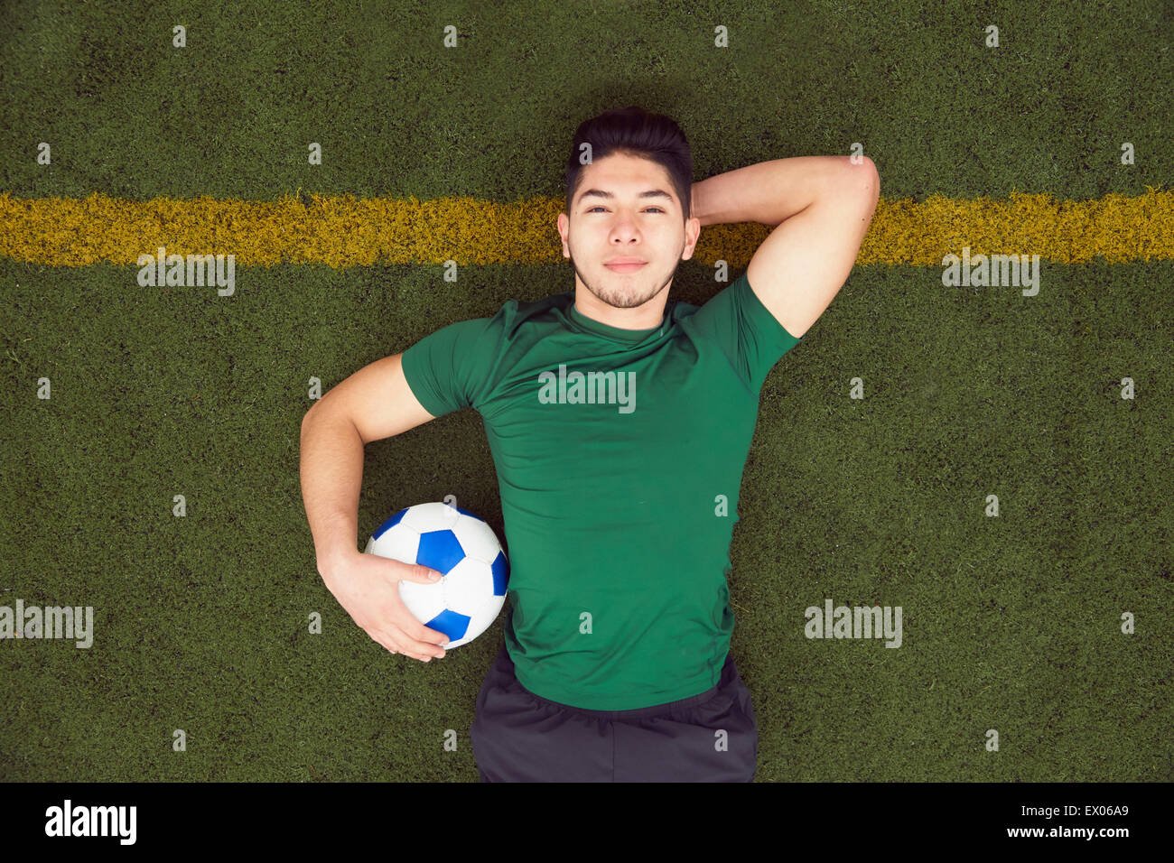 Obenliegende Porträt des jungen männlichen Fußballer am Fußballplatz liegen Stockfoto