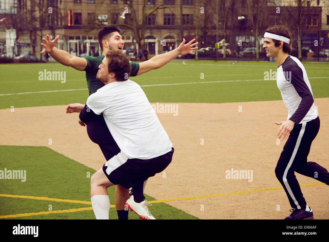 Drei männliche Fußballer feiert am Fußballplatz Stockfoto