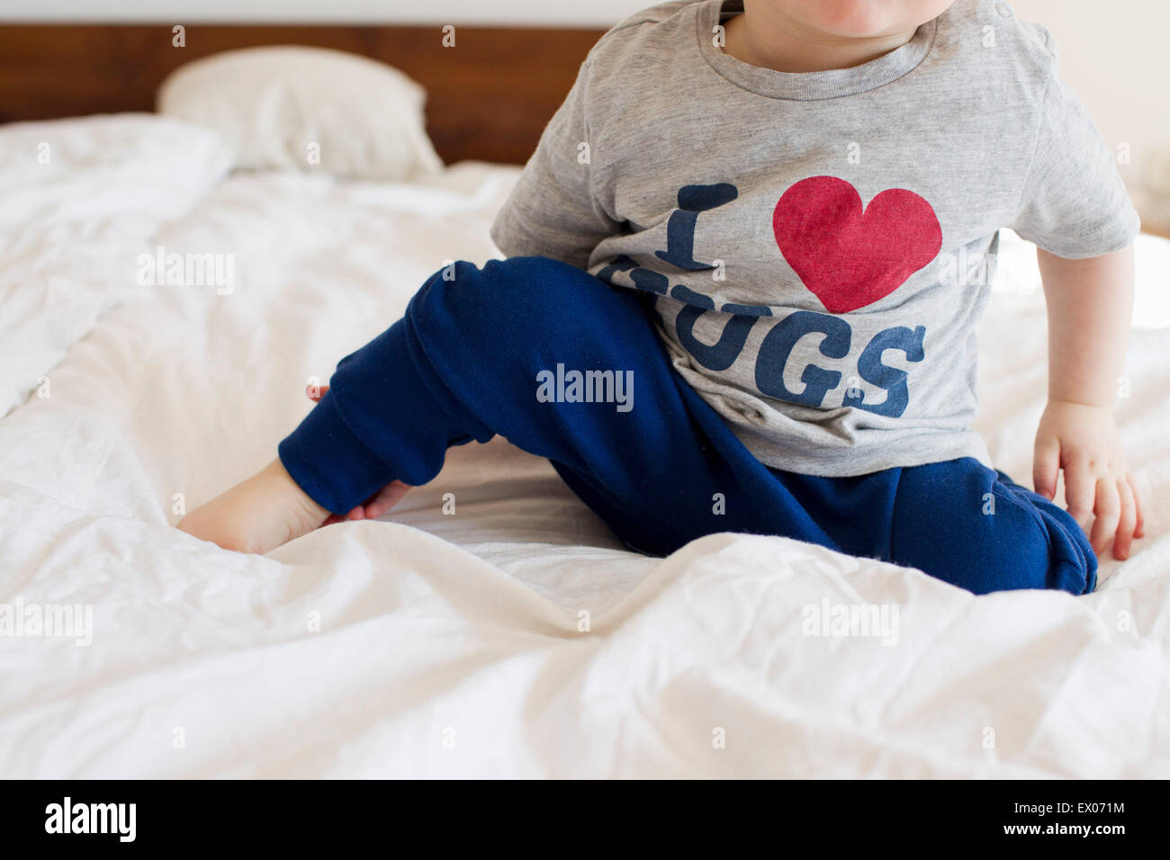 Schuss von Babymädchen trägt Pyjama im Bett sitzend beschnitten Stockfoto