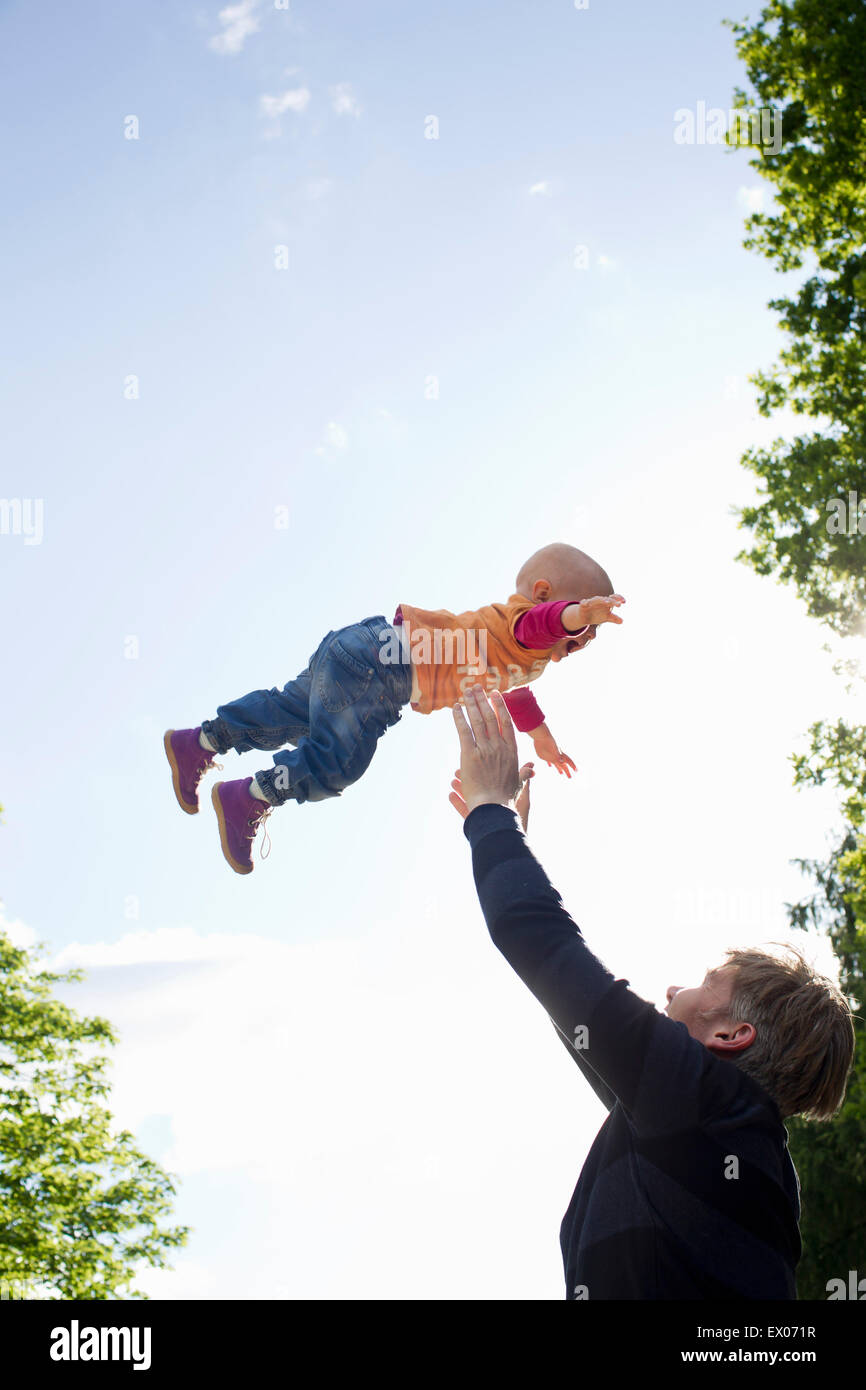 Vater wirft Tochter Mitte Luft im park Stockfoto