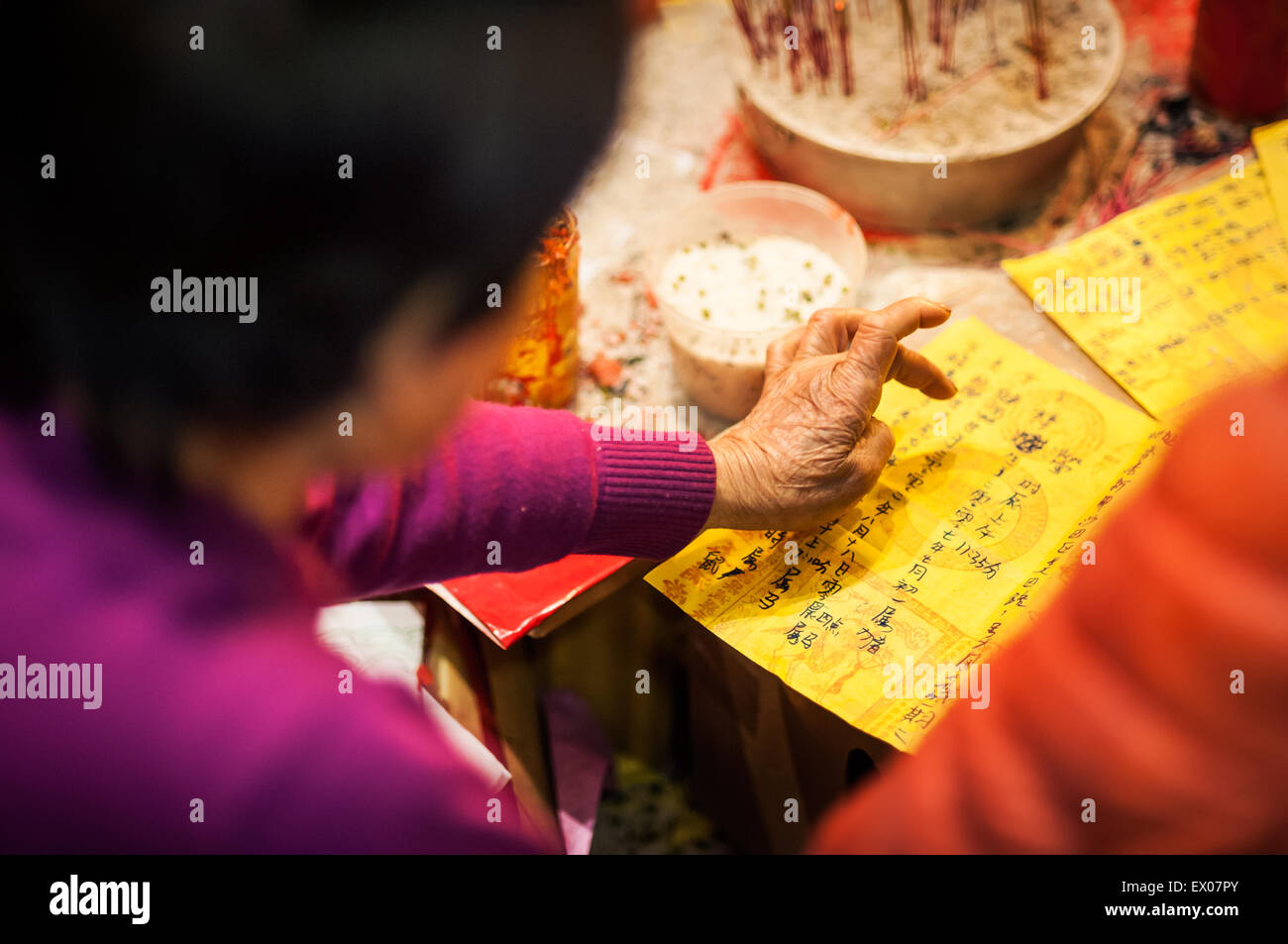 Eine alte Frau liest ein Diagramm während einer Zeremonie "Bösewicht schlagen" in Hong Kong Stockfoto