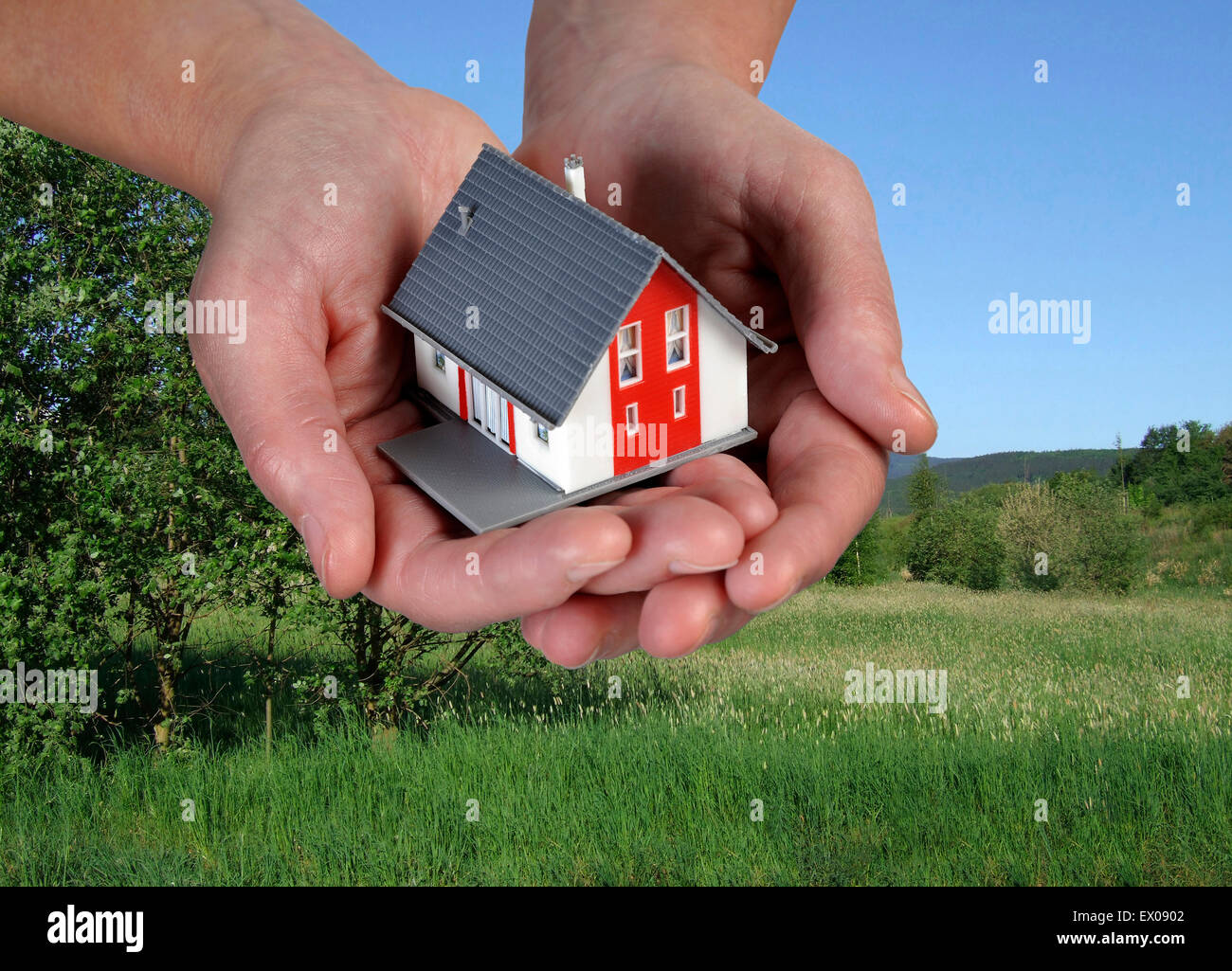 Hände mit Hausfront von einer grünen Wiese. Stockfoto