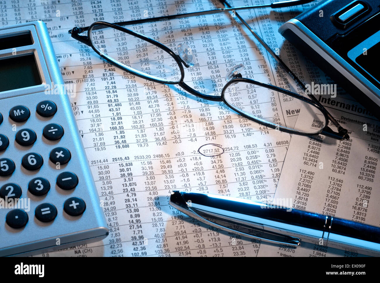 Aktienkurs mit Brille, Taschenrechner und Stift markiert. Stockfoto