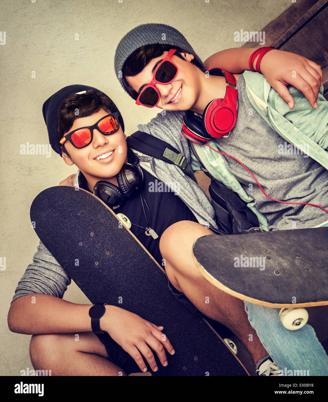 Zwei glückliche stilvolle Teen Boys auf der Bank sitzen und halten Skateboards, sport fröhlich aktive Freunde genießen im freien Stockfoto