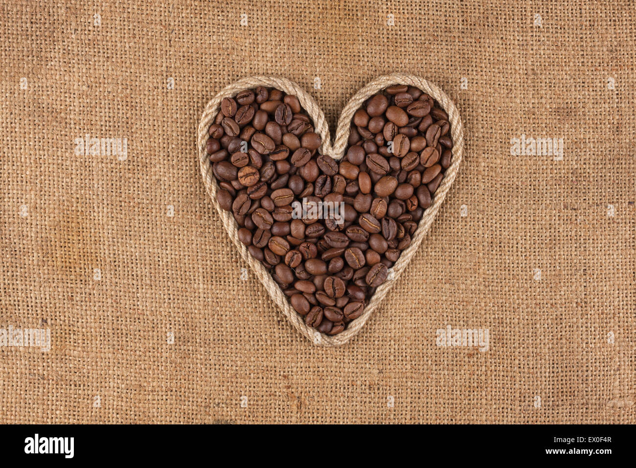Herz aus Seil mit Kaffeebohnen liegen auf Sackleinen, mit Platz für text Stockfoto