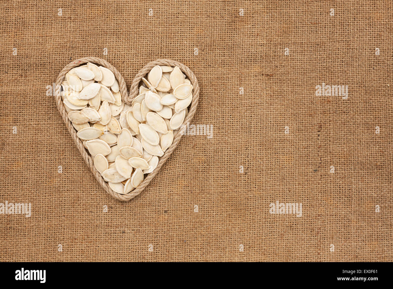 Herz aus Seil mit Kürbiskernen liegen auf Sackleinen, mit Platz für text Stockfoto
