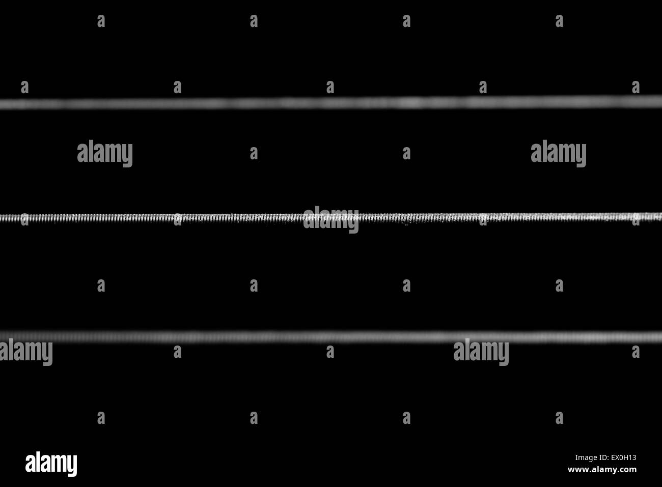 Eine dramatische 1:1-Makroaufnahme der akustischen Gitarrensaiten gerahmt horizontal über den Rahmen in schwarz und weiß. Stockfoto