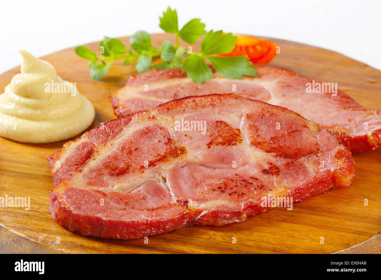 Scheiben von geräuchertem Schweinenacken und Senf Stockfoto