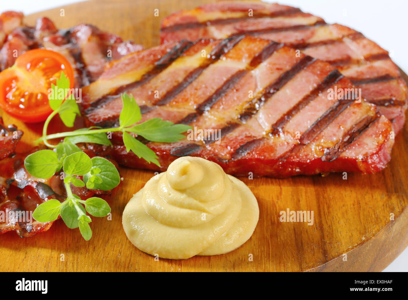 Scheiben von geräuchertem Schweinenacken und Senf Stockfoto