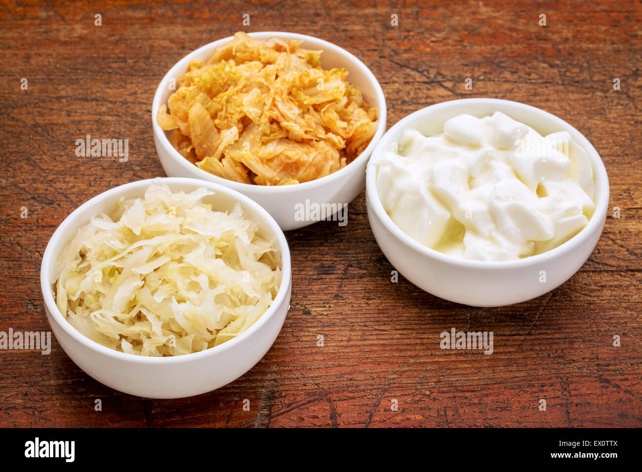 Sauerkraut, Kimchi und Joghurt - fermentiert beliebte probiotische Lebensmittel - drei Keramikschale gegen rustikale Holz Stockfoto