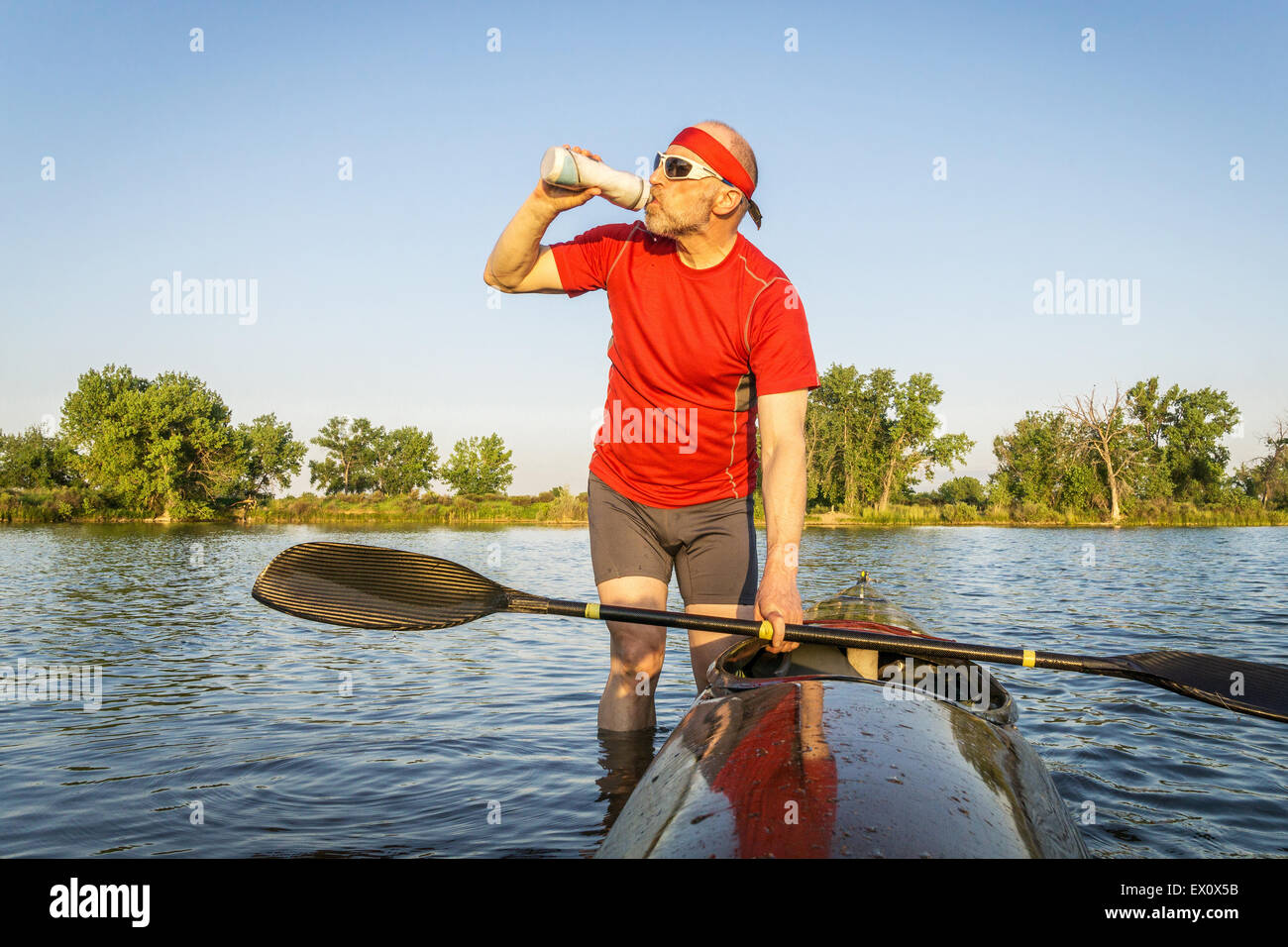 nach dem Training auf einem See paddeln, im Sommer trinken Senior Kajak Paddler Trinkwasser oder sport Stockfoto