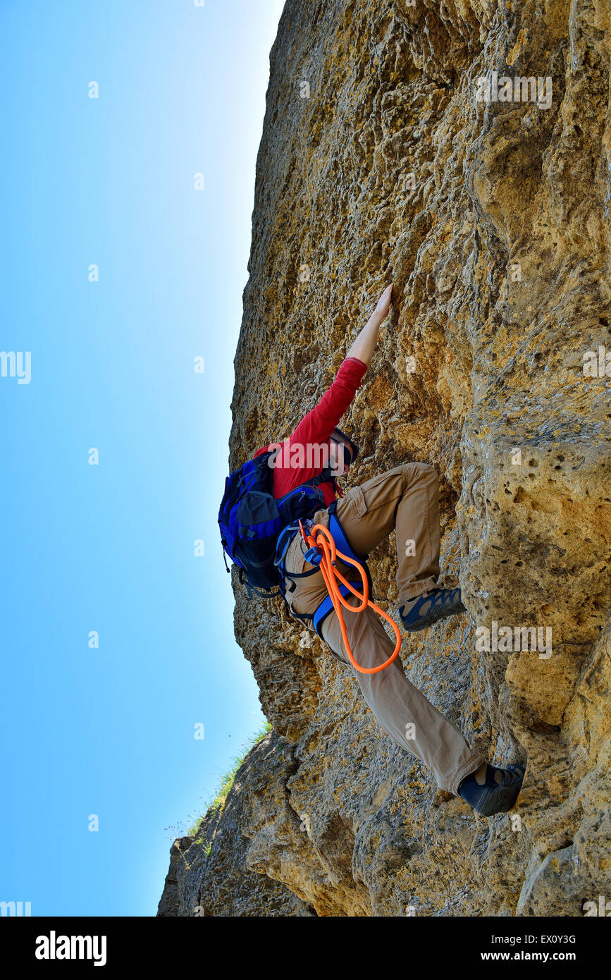 Junger Mann mit Rucksack Outdoor-Kletterwand Stockfoto