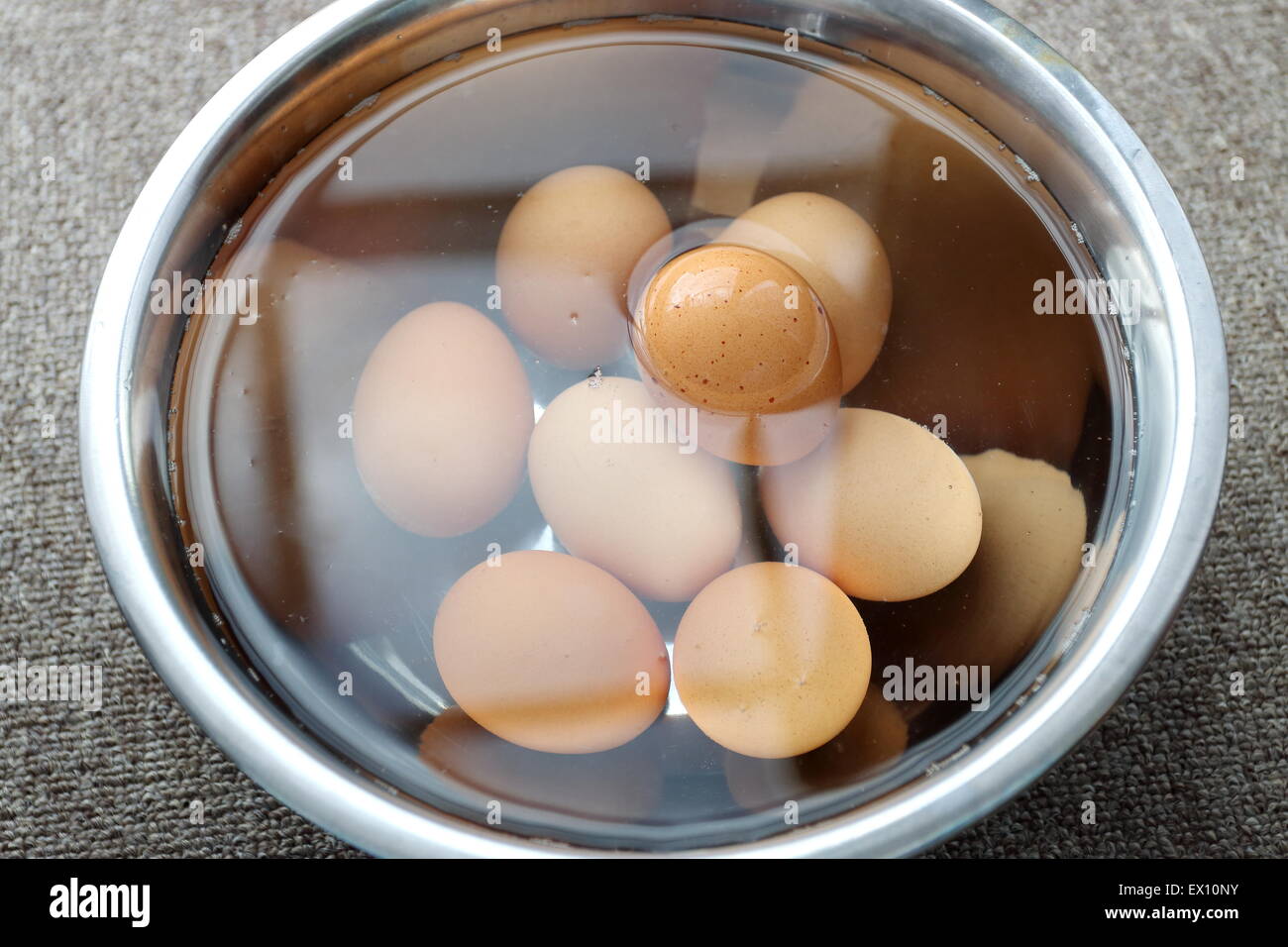 Einweichen braune Eier in Edelstahl Schüssel mit Wasser Stockfoto