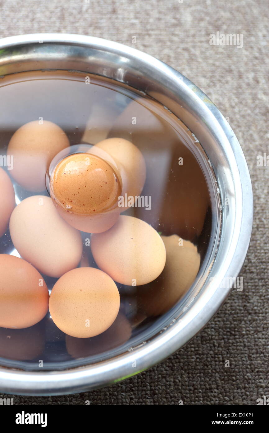 Braunen Eiern in eine Edelstahl-Schüssel mit Wasser Stockfoto