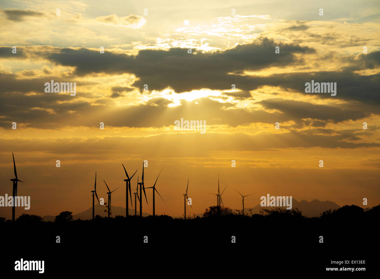 Windkraftanlagen als Silhouetten gegen einen wunderschönen Sonnenuntergang mit Sonnenstrahlen scheint herab Stockfoto