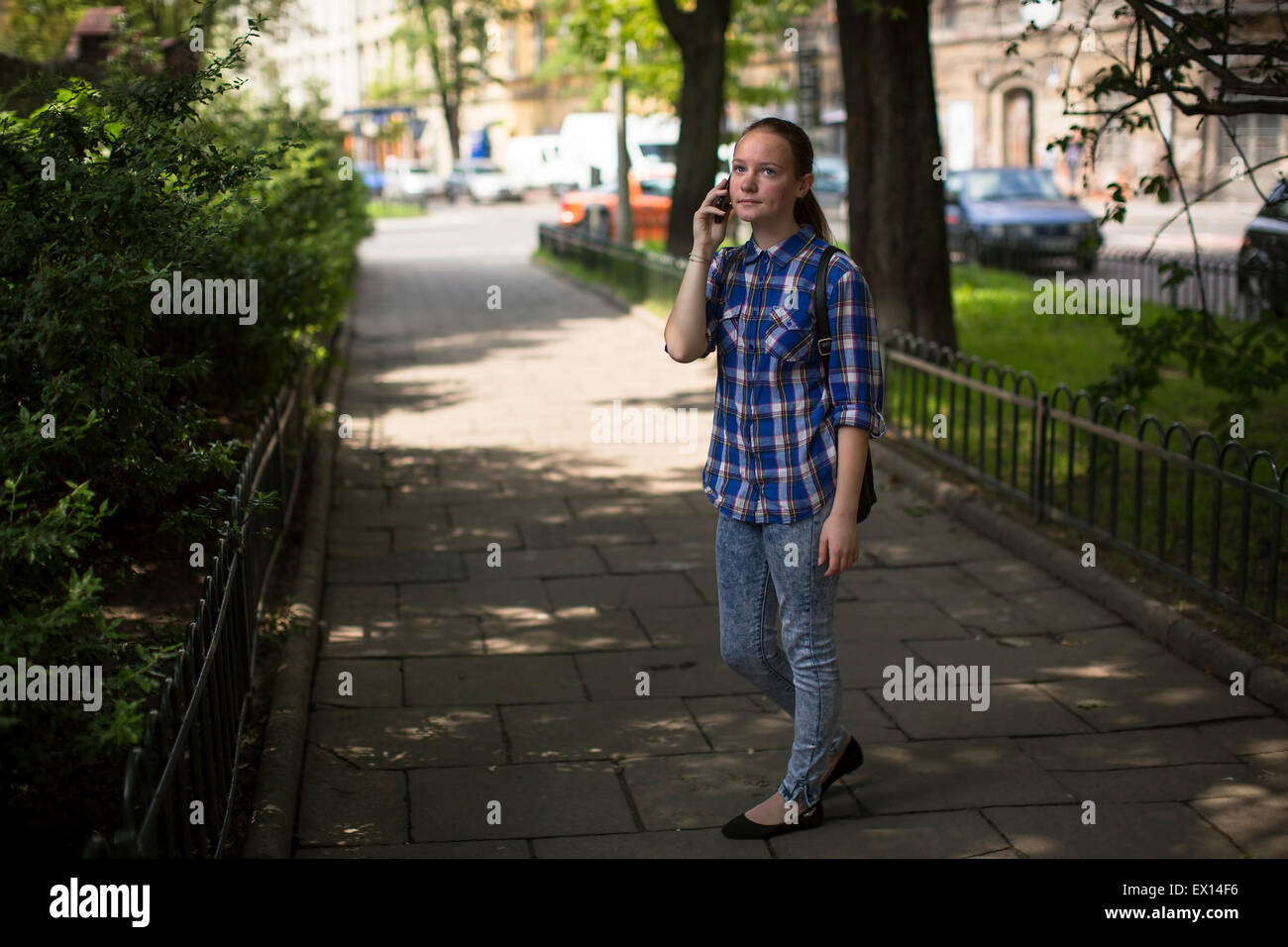 Teenager-Mädchen ruft ein Handy auf der grünen Gasse stehen. Stockfoto