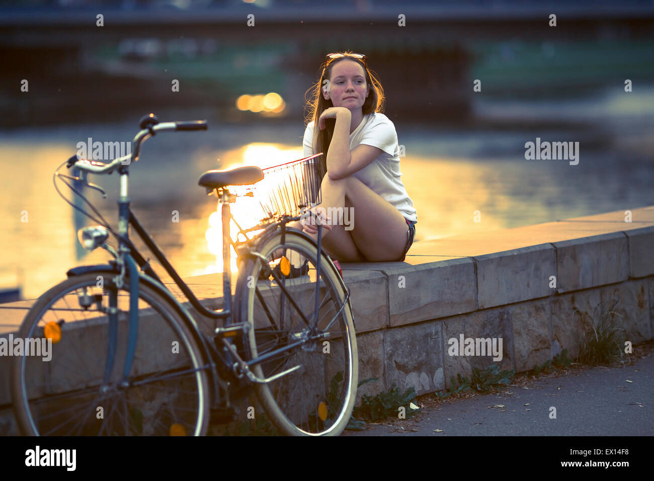 Teenager-Mädchen mit dem Fahrrad, sitzen auf der Promenade während des Sonnenuntergangs. Prozess-Film-Stil zu überqueren. Stockfoto