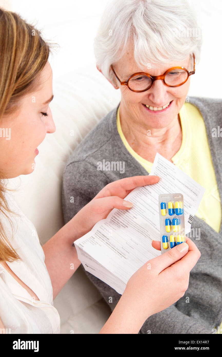 -MODELL VERÖFFENTLICHT. Eine junge Frau, die verschreibungspflichtige Medizin Broschüre zu einem Senor Frau lesen. Stockfoto