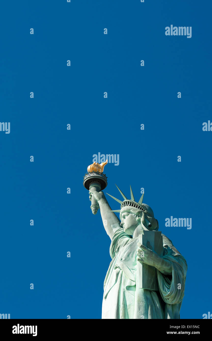 Profil-Blick auf die Freiheitsstatue mit ihrer Fackel gegen klar strahlend blauer Himmel Stockfoto