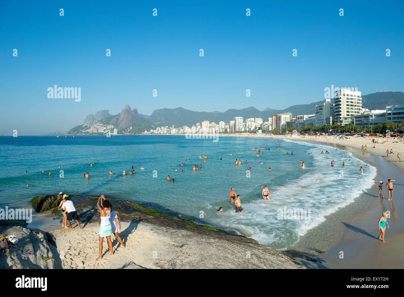 RIO DE JANEIRO, Brasilien - 17. Januar 2015: Beachgoers entspannen Sie sich auf den Felsen am Strand von Ipanema Arpoador Ende mit Skyline der Stadt. Stockfoto
