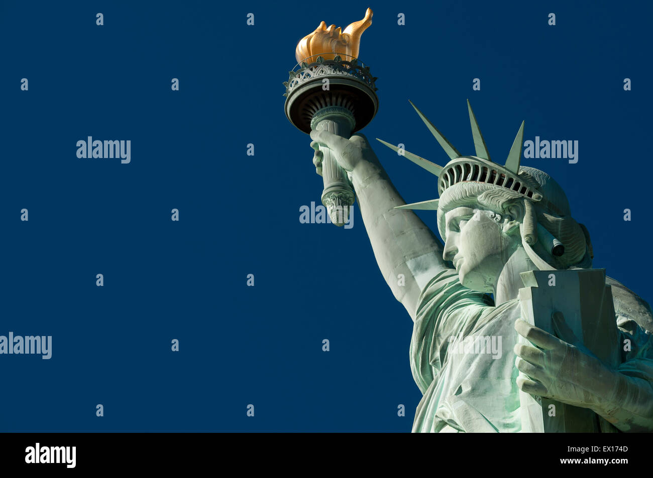 Profil-Blick auf die Freiheitsstatue mit ihrer Fackel gegen klar strahlend blauer Himmel Stockfoto