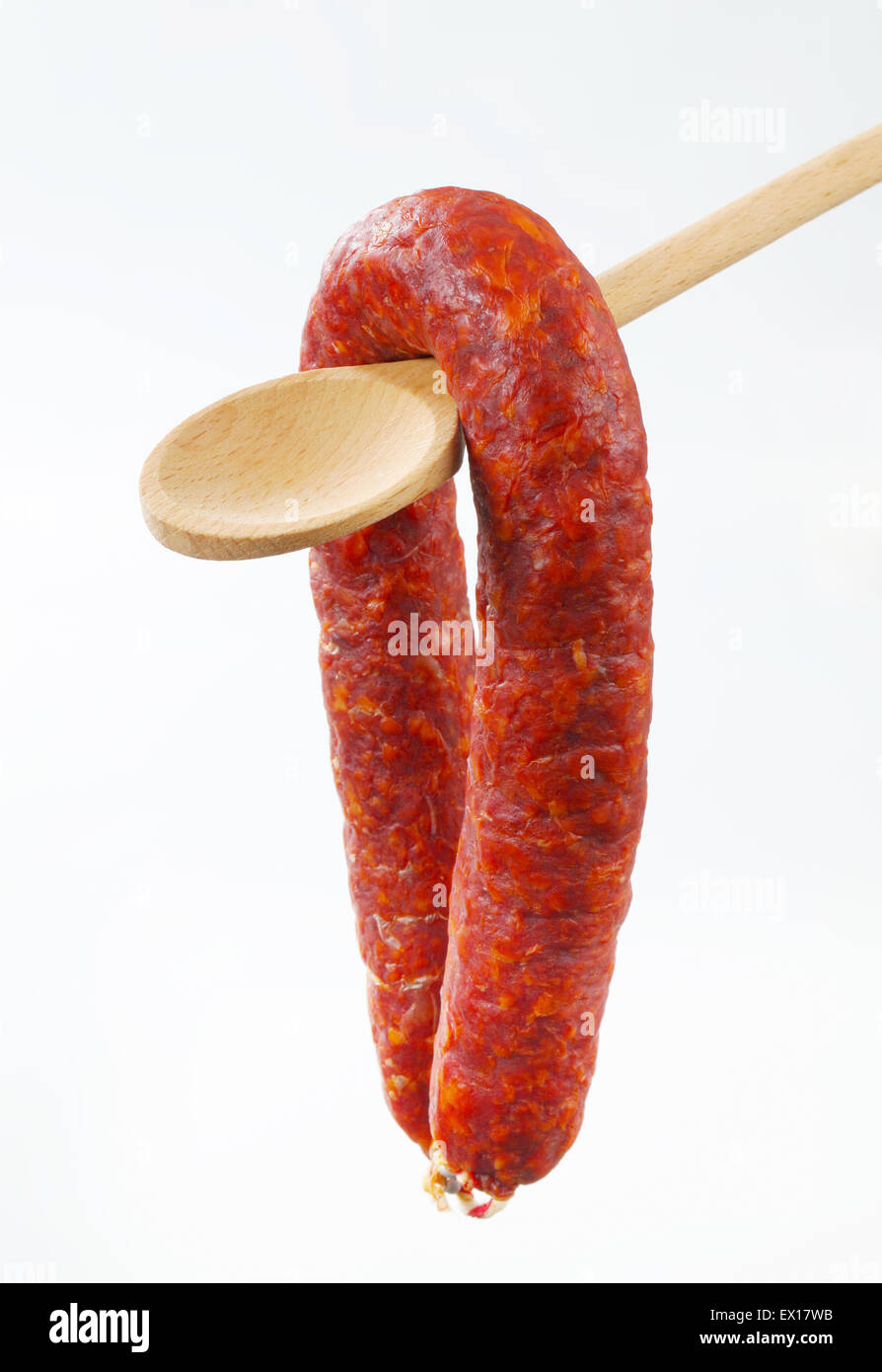 Würzige Wurst auf Holzlöffel Stockfoto