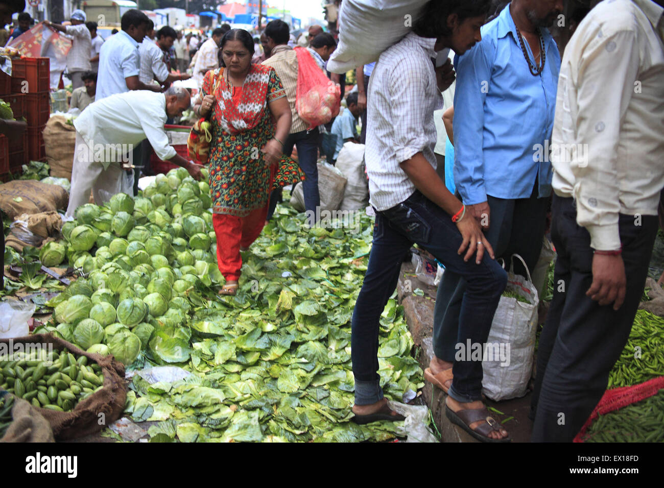 22. August 2014 - 22. August 2014 - Mumbai, Indien:. Eine Frau für Gemüse einkaufen geht auf einen Haufen ausrangierten & Abfall Gemüse auf dem Gemüsemarkt Dadar in Mumbai. Hunderte von Tonnen Gemüse sind auf einer täglichen Basis auf dem Gemüsemarkt Dadar verschwendet. Indien, der weltweit größte Produzent von Milch und der zweitgrößte Produzent von Obst und Gemüse, ist auch einer der größten Lebensmittel-Verschwender in der Welt - 440 Milliarden Rupien Wert von Obst, Gemüse und Getreide jährlich nach Emerson Climate Technologies India, Teil von Emerson, einem US-amerikanischen Fertigung und Techno zu verschwenden Stockfoto