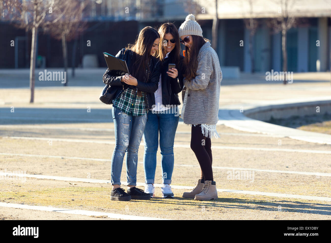 Porträt von drei Studenten Mädchen mit Handy auf dem Campus. Stockfoto