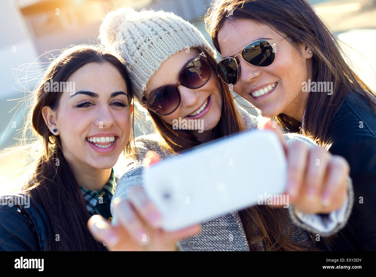 Porträt von drei Studenten Mädchen mit Handy auf dem Campus. Stockfoto