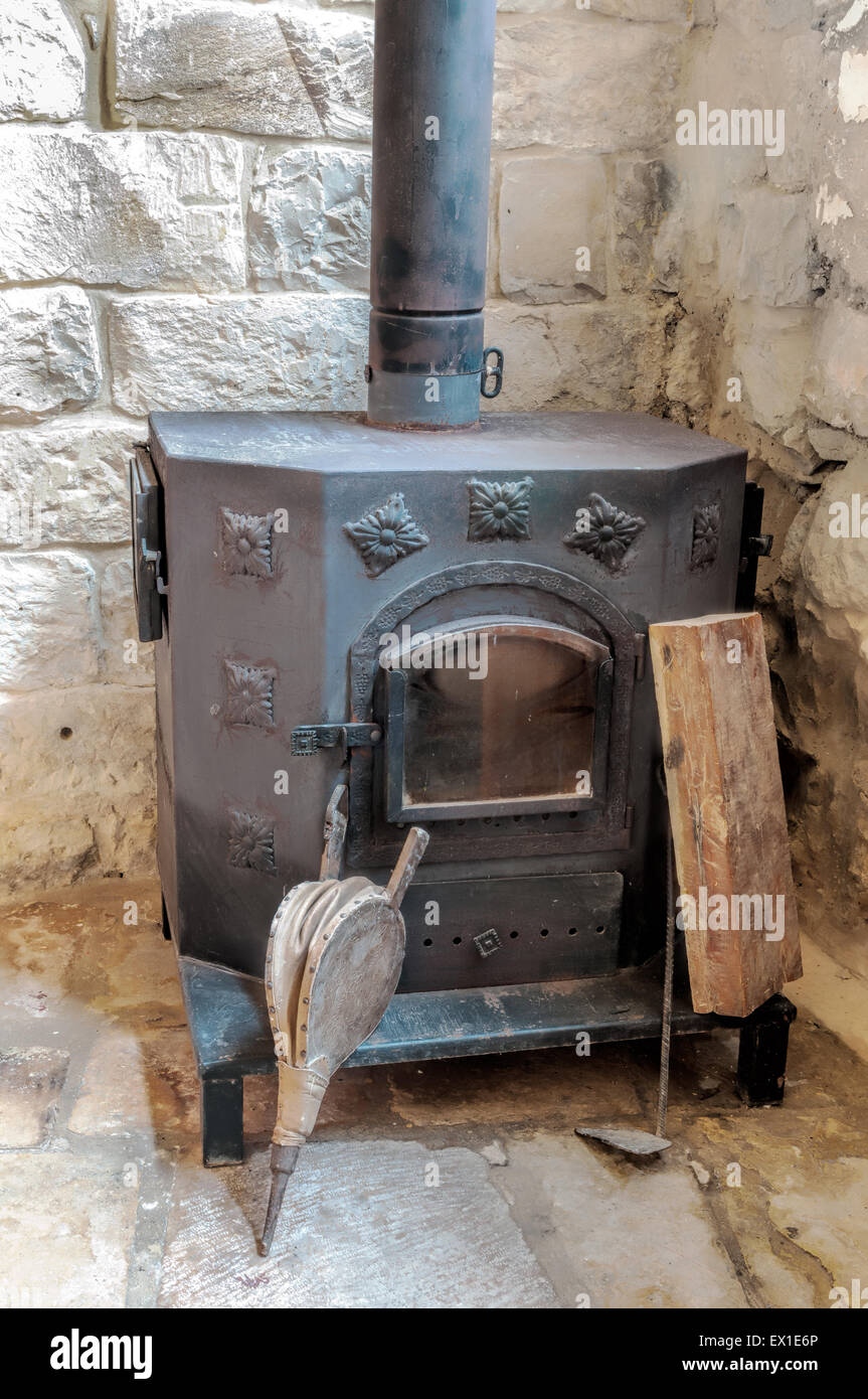 Antiken Kamin des black Metal ist in der Ecke eines großen Steinhaus Stockfoto