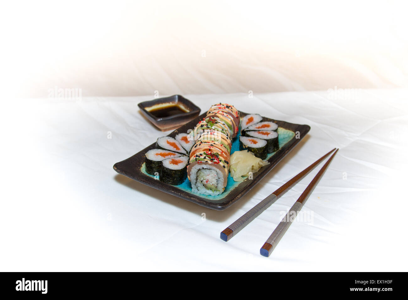 Sushi-Rollen, Stäbchen, Wasabi und Ingwer auf einem Teller auf weißem Hintergrund Stockfoto