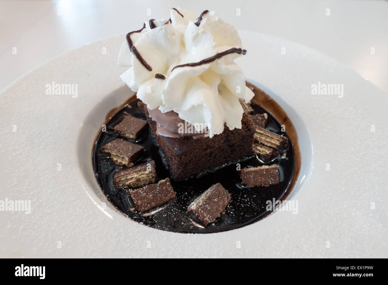 Chocolate Fudge Kuchen und Eis auf Schokoladensauce und Waffel mit Sahne obenauf Stockfoto