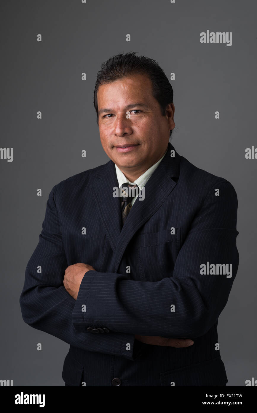 Hispano-Amerikaner Geschäftsmann lächelnd mit verschränkten Armen in einem Business-Anzug posieren für ein Porträt Stockfoto