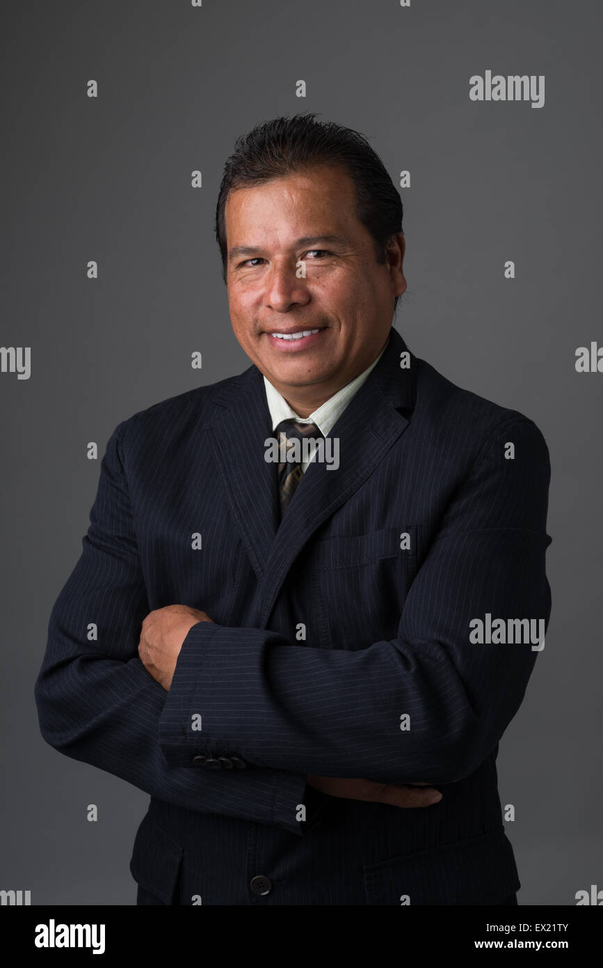 Hispano-Amerikaner Geschäftsmann lächelnd mit verschränkten Armen in einem Business-Anzug posieren für ein Porträt Stockfoto