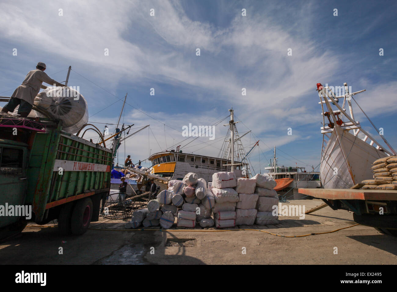Eine Szene, die Fracht, Lastwagen, traditionelle pinisi-Schiffe und Arbeiter an einem heißen Tag im Hafen von Paotere, Makassar, South Sulawesi, Indonesien zeigt. Stockfoto