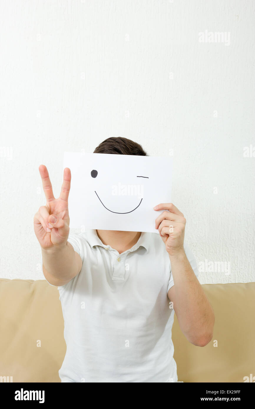 Mann mit 2 Fingern, Hand Siegeszeichen, Anzahl. Konzept-Foto von Friedenssymbol. Erwachsene junge bedecken sein Gesicht mit glücklich Augenzwinkern Lächeln Stockfoto