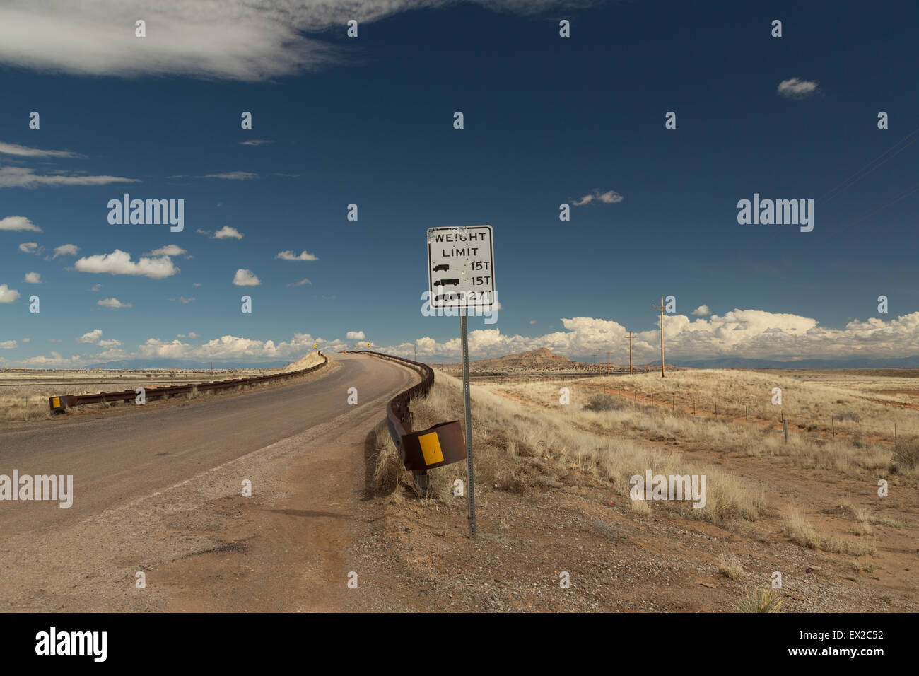 Ein Foto vom Eingang zu einer gekrümmten Brücke in der Wüste von New Mexico, USA. Ein Schild "Gewichtsgrenze" steht im Vordergrund. Stockfoto