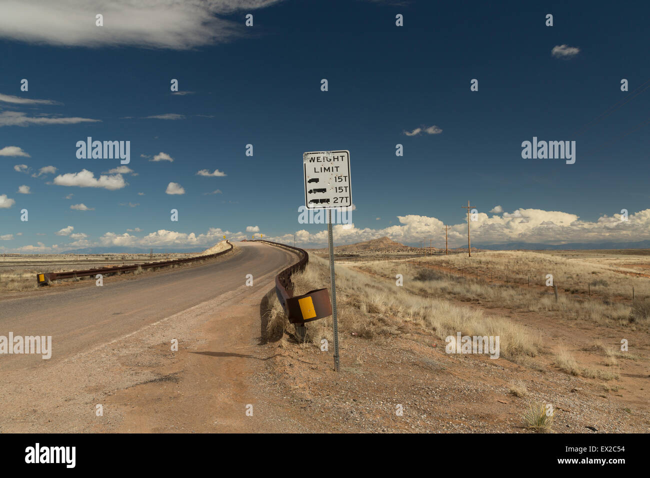 Ein Foto vom Eingang zu einer gekrümmten Brücke in der Wüste von New Mexico, USA. Ein Schild "Gewichtsgrenze" steht im Vordergrund. Stockfoto