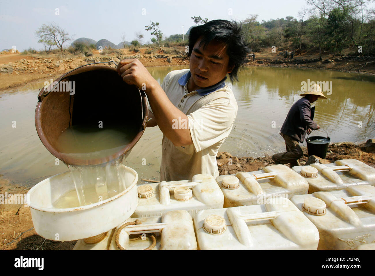 Ein Anwohner nehmen Sie Wasser aus einem Teich in einem Dorf im Mengzi county, Provinz Yunnan 28. Februar 2010.  VCP Stockfoto