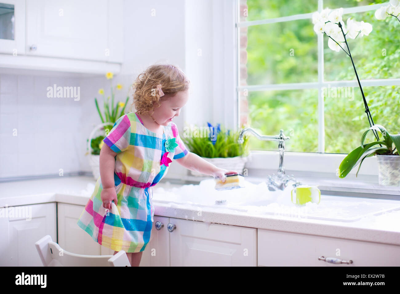 Kind abwaschen. Kinder waschen Teller und Tassen. Kleines Mädchen
