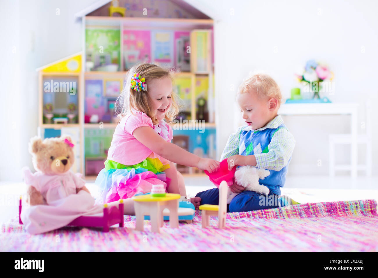Kinder spielen mit Puppenhaus und tierischen Plüschtiere. Kinder sitzen auf  einem rosa Teppich im Spiel zu Hause oder im Kindergarten Stockfotografie -  Alamy