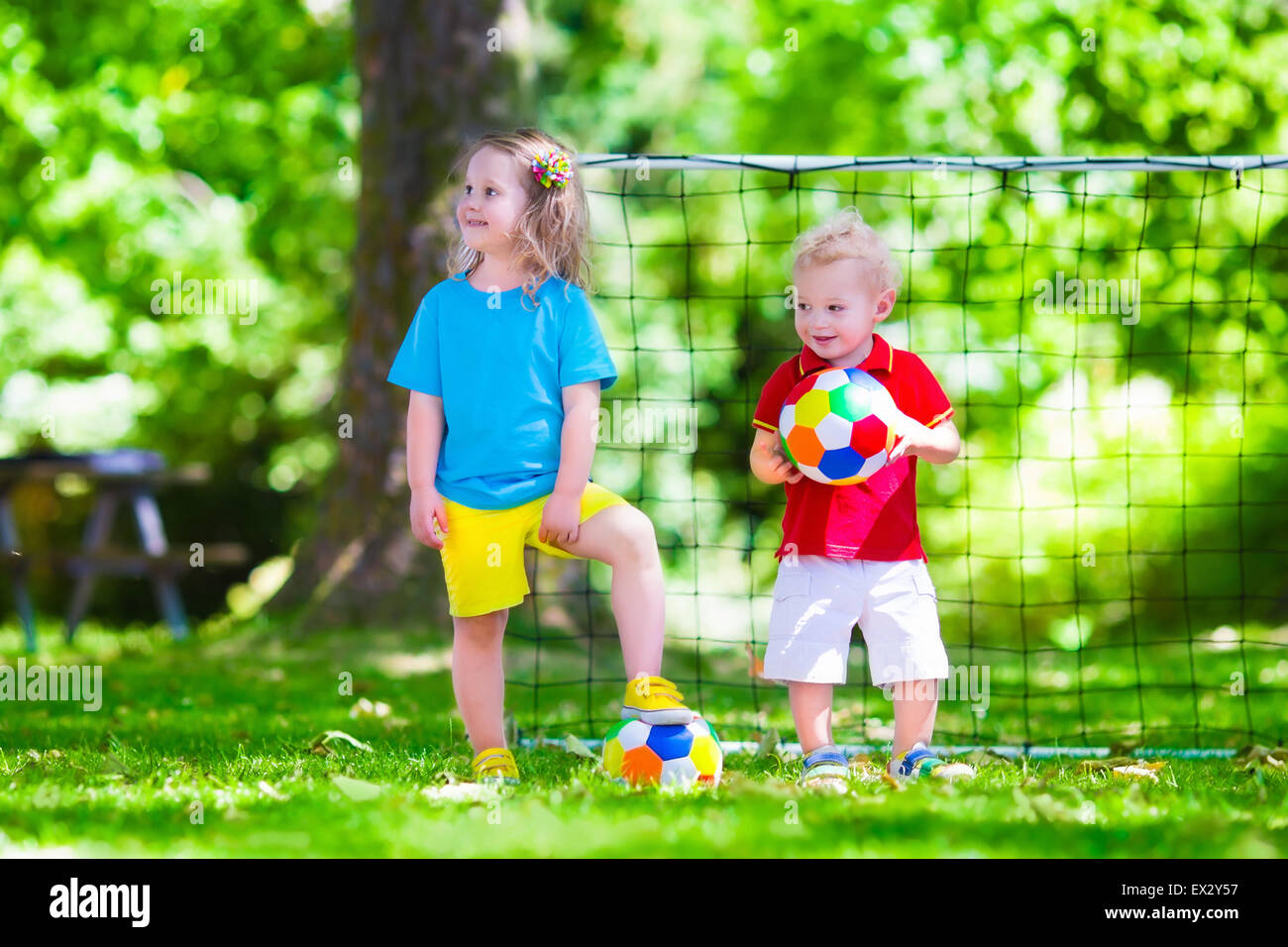 Zwei glückliche Kinder spielen Fußball im Freien im Schulhof. Kinder spielen Fußball. Aktiv Sport für Vorschulkind. Stockfoto