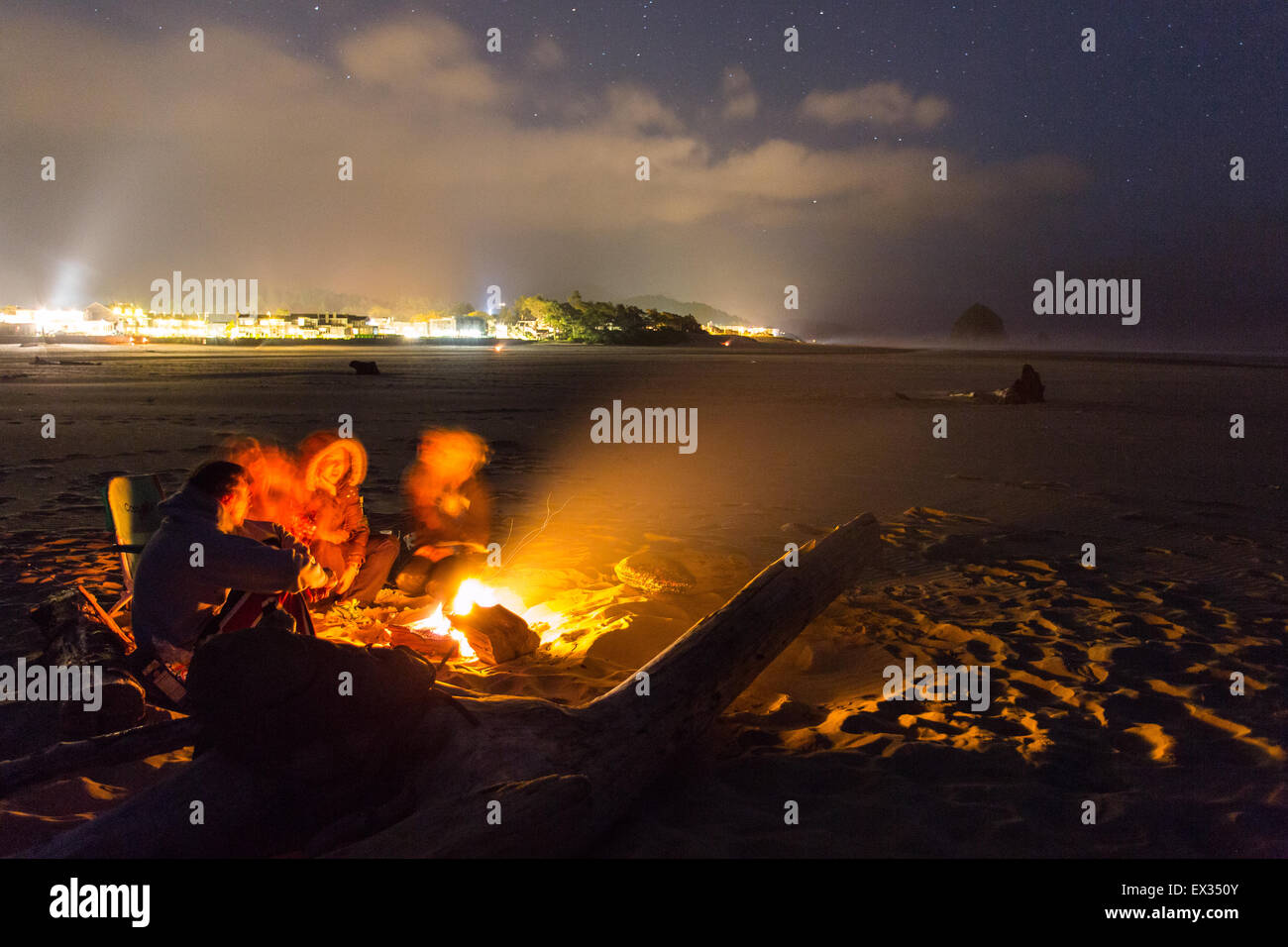 Ein paar Freunde versammeln sich um ein Strand-Lagerfeuer unter dem Sternenhimmel in Cannon Beach, Oregon. Stockfoto