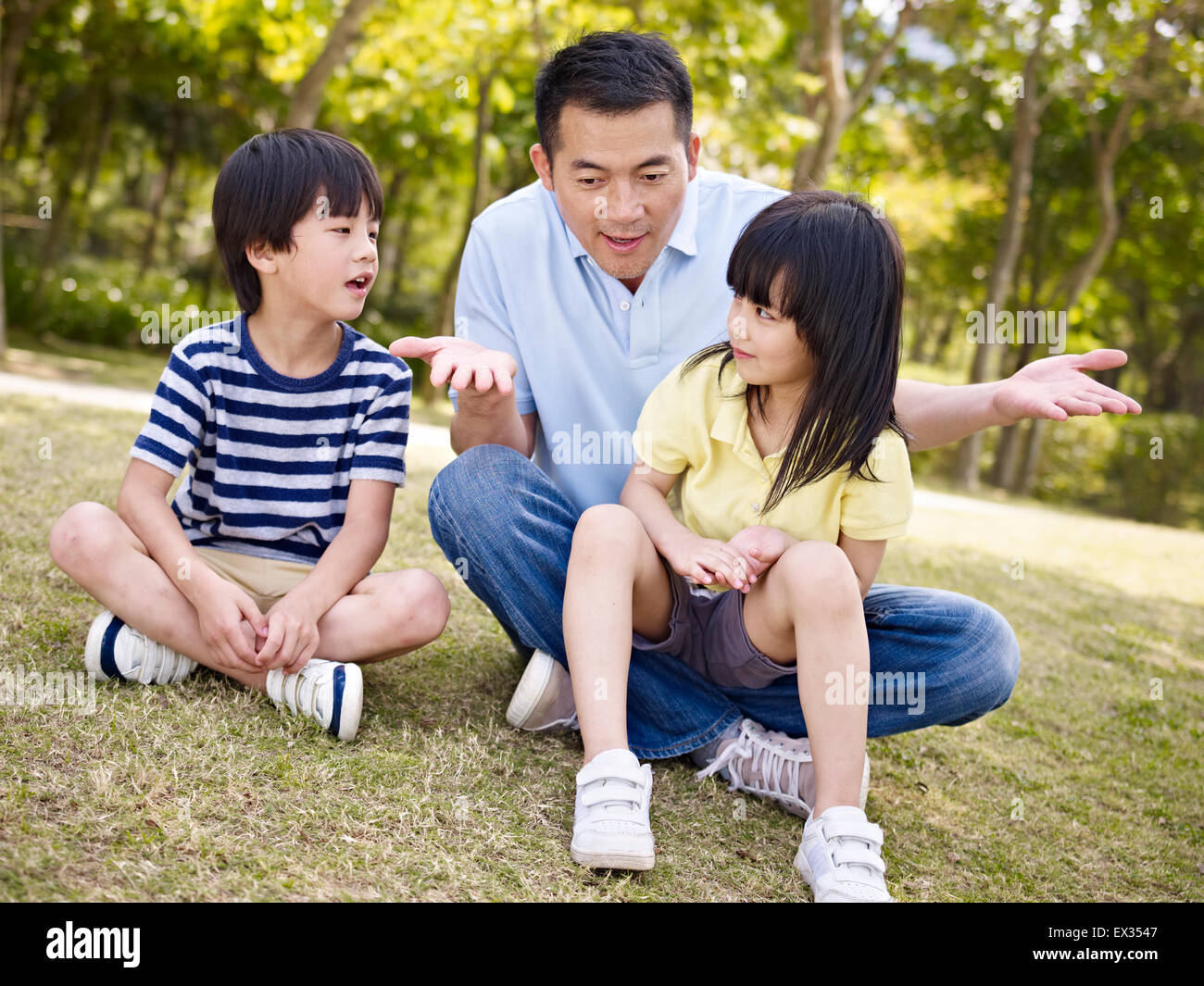 asiatischen Vater und Kinder sprechen im park Stockfoto