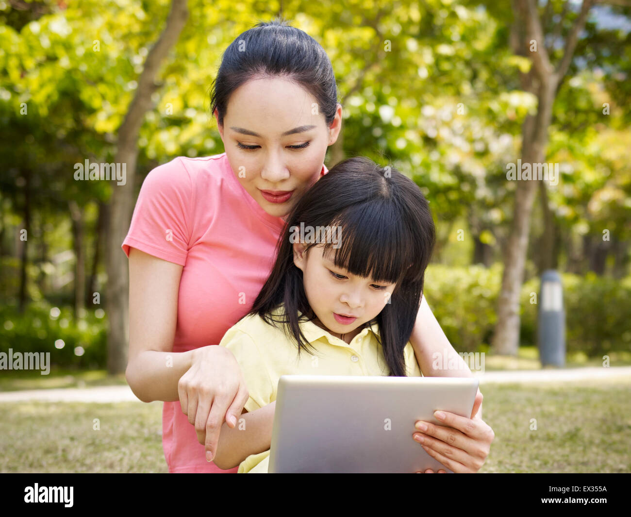 asiatische Mutter und Tochter mit dem Ipad im freien Stockfoto